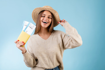 beautiful woman with boarding pass plane tickets in passport and tourist hat isolated over blue