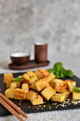 Fried tofu with soy sauce on a wooden board.