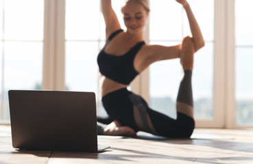 Fototapeta premium Yoga girl exercising in front of laptop