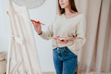 cropped shot of woman artist drawing picture with bright colors on canvas in studio workshop
