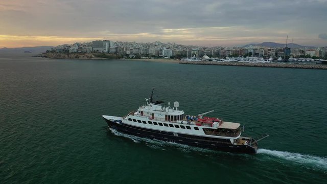 Aerial drone photo of yacht cruising leaving Marina Zeas at sunset with beautiful colours, Piraeus, Attica, Greece