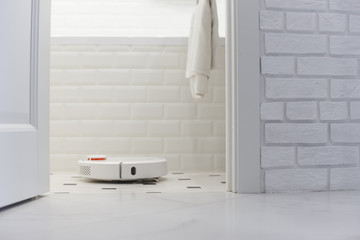Fototapeta na wymiar White robot vacuum cleaner in bathroom
