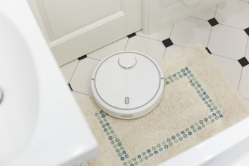 White robot vacuum cleaner on carpet in bathroom