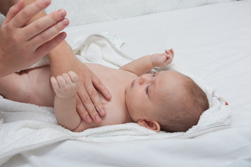 Mother hand cleaning baby ear and nose with a cotton swab. Baby taking care and hygiene concept.