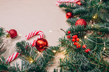 craft background with christmas tree and balls closeup. Free space for text. Red Christmas balls, branches of spruce, candy in the form of sticks. Christmas background