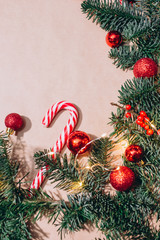 craft background with christmas tree and balls closeup. Free space for text. Red Christmas balls, branches of spruce, candy in the form of sticks. Christmas background