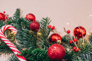 craft background with christmas tree and balls closeup. Free space for text. Red Christmas balls, branches of spruce, candy in the form of sticks. Christmas background