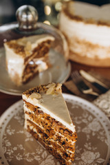 beautiful Healthy Homemade Carrot Cake on plate on the background of a blurred whole cake on a stand