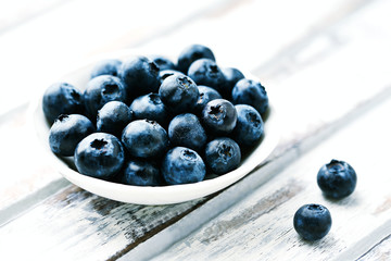 Bilberries on white wooden background. Close up.