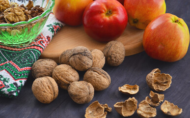 Ripe apples and walnuts on the table. Peeled nuts and shelving from them.
