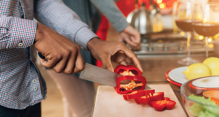 African-american man cutting bell pepper in kitchen