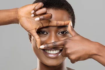 Foto op Aluminium Beautiful african woman holding frame from fingers near her eyes © Prostock-studio