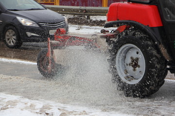 New red Tractor with outboard snow blower broom cleaning asphalt road after snow fall in winter day...