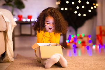 Shocked happy african american little girl enjoying Christmas gift