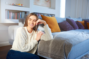 Closed eyes young woman smiling while relaxing on sofa at home