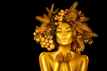 Christmas golden Woman. Winter girl pointing Hand, blowing, holding product Beautiful New Year, Christmas Tree Holiday Hairstyle and gold skin Makeup. Gift. Girl in decorated Xmas wreath. Beauty Model