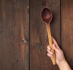hand holds an old brown wooden spoon