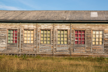 Old residential wooden houses. Windows and walls with damaged old roof with weathered paint. To close. On the street in the Arkhangelsk region of Russia.