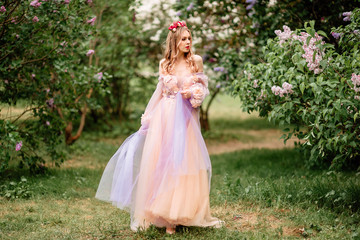 Plakat Beautiful romantic fairy girl in long dress in blooming spring garden. Gorgeous young model with perfect hairstyle in fairy forest. Fantasy art