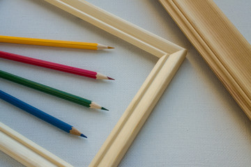 Colored pencils in a wooden frame on a white canvas