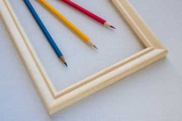Colored pencils in a wooden frame on a white canvas