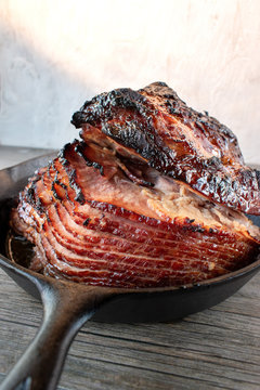 slices of rustic holiday honey glazed baked ham in cast iron pan