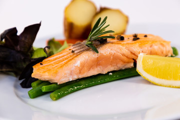 Grilled fresh salmon steak with roasted green beans, baked potatoes, lime and salad vegetables is a healthy diet for dieting on a plate.