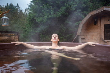 beautiful young woman relaxing in an outdoor hot tub on the forest. Otzarreta, Basque Country, Spain - obrazy, fototapety, plakaty