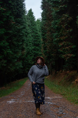 beautiful young woman with hat, sweater and skirt walking on a pine forest path. Otzarreta, Basque...