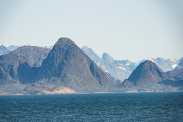 Fototapeta na wymiar Arctic landscape in summer with high mountains and icebergs floating on the sea in Ofjords, Scoresby Sound, East Greenland
