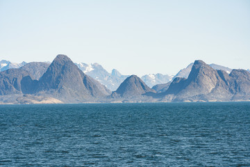 Arctic landscape in summer with high mountains and icebergs floating on the sea in Ofjords, Scoresby Sound, East Greenland