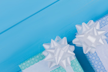 Decorative gift boxes with bow wrapped in patterned paper. Top view. Blue wood background.