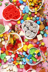 candies with jelly and sugar. colorful array of different childs sweets and treats on pink background