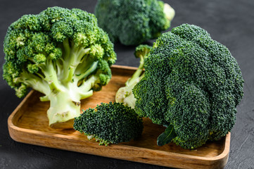 Raw broccoli in a wooden bowl. Black background. Top view