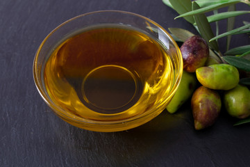 glass vessel with extra virgin olive oil and natural olives with olive branches