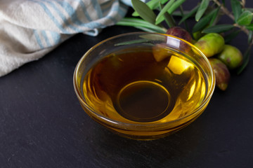 glass vessel with extra virgin olive oil and natural olives with olive branches