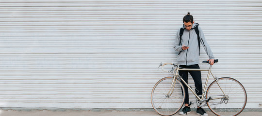 young man with mobile phone in the street and vintage bicycle with space for text or announcements