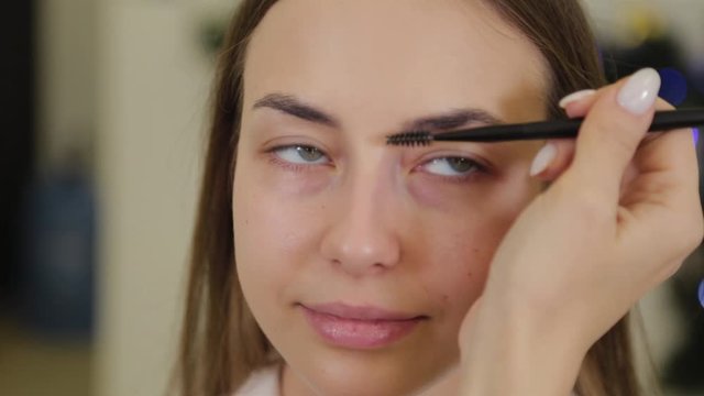 Professional makeup artist paints eyebrows to a client of a beauty salon.