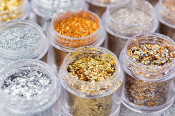 Beautiful glitter close up in golden and silver tones in small glass jars, selective focus
