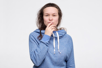 Female teenager in blue clothes trying to make a deccision and hard choice.