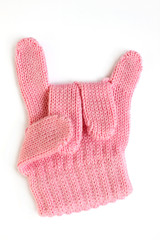 Sign hand rock & roll heavy metal on white. A demonstration of the sign of the horns. Children's pink glove for a little girl. Knitted winter accessory isolated.
