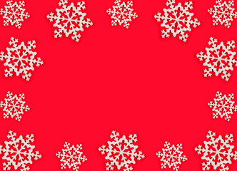 Frame made of white snowflakes over red festive background. Copy space.