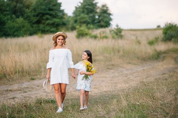 Naklejka na ściany i meble Mother and daughter having fun in the park. Happiness and harmony in family life. Beauty nature scene with family outdoor lifestyle. Mother's Day