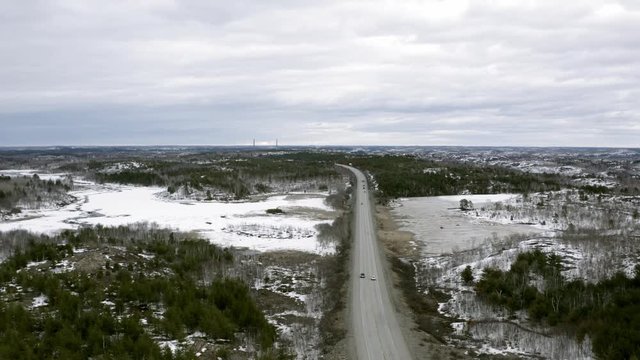 Drone shot descending on vehicles driving on a cold northern road