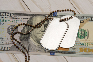 On the hundred-dollar bill are army identification medallions. Concept: military pension, salary in...