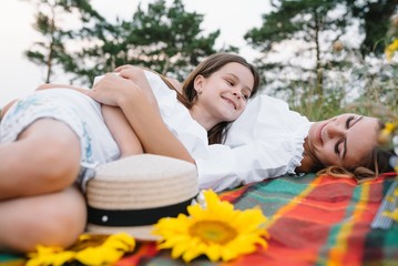 Top view of happy woman smiling and playing with her cute little child, lying outdoor.Loving mother and daughter spend time together in a park. Mom and kid has fun. Mother's day