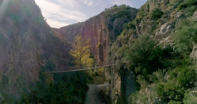 Anciano cruzando puente colgante de barranco mediterr&aacute;neo y dron acerc&aacute;ndose