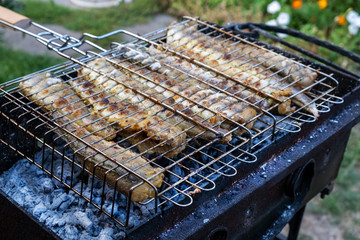 Grilled seafood. Hake Fish on a grill plate outdoors. Cooking Roasted fish on the open fire. Men's hand turn over fish in the lattice on the barbecue. Village lifestyle