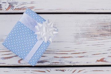 Blue gift box and copy space. Present box wrapped in blue patterned paper with satin ribbon. Holiday greeting card.