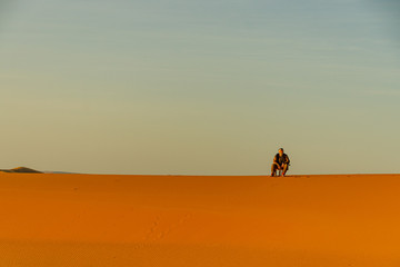 Fototapeta na wymiar Man sitting in the Sahara desert in Merzouga. Morocco